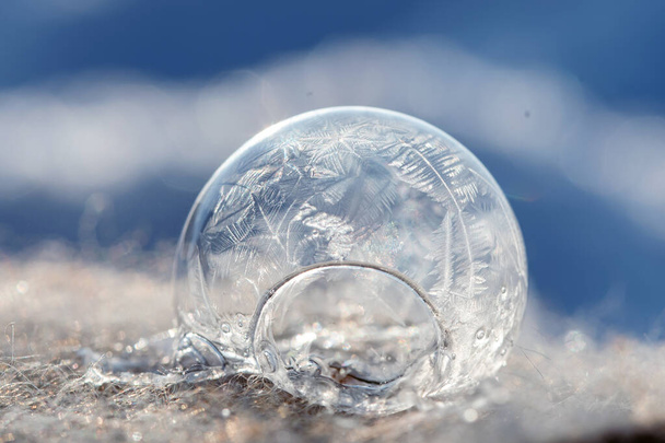 Frozen soap bubble with a beautiful pattern on the snow close-up on a blurry background. - Φωτογραφία, εικόνα