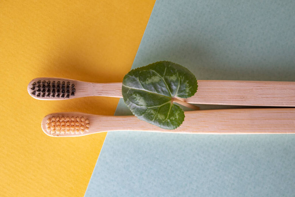 Sarı ve mavi arkaplanda iki bambu diş fırçası var. Ekoloji, diş hijyeni ve sağlık kavramı. Mesaj için yer. Yapıştırıcı kopyala. - Fotoğraf, Görsel