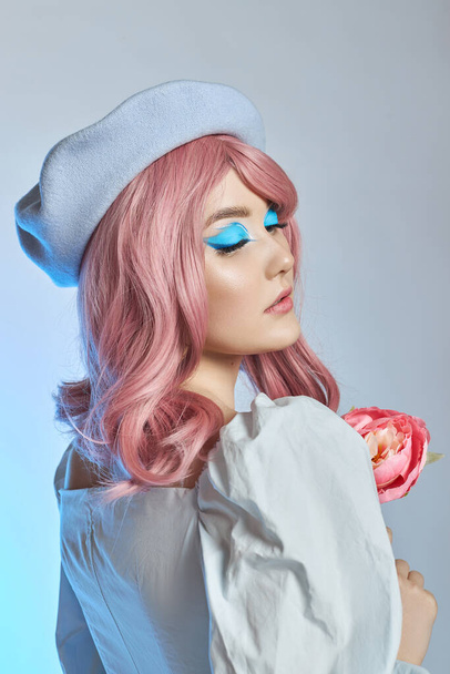 Romantic woman with pink hair in a blue beret on her head, a French woman with a rose in her hands. Blue makeup on the eyes eyelids of a young woman - Foto, imagen