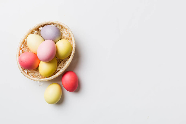 Multi colors Easter eggs in the woven basket on colored background . Pastel color Easter eggs. holiday concept with copy space. - Fotografie, Obrázek