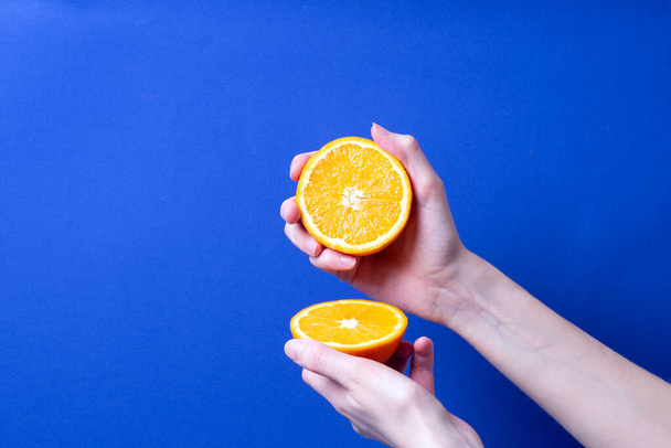жіноча рука тримає вирізаний стиглий апельсин
 - Фото, зображення