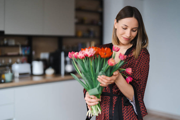 Jovem mulher gosta de flores em casa - Foto, Imagem