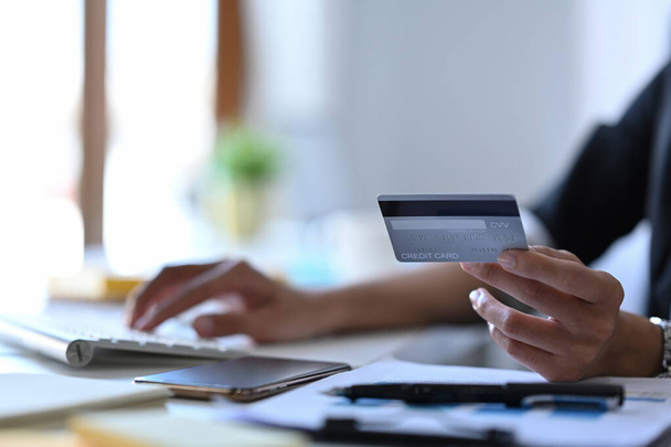 Fermer femme d'affaires détenant une carte de crédit et utilisant l'ordinateur pour les opérations bancaires en ligne. - Photo, image