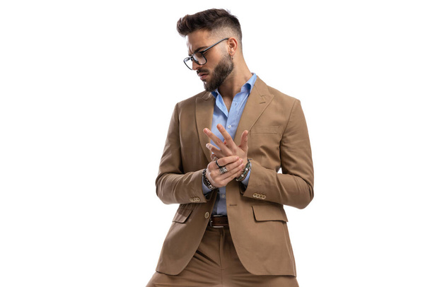 handsome bearded man with glasses looking to side, rubbing and massaging hands on white background in studio - Photo, image