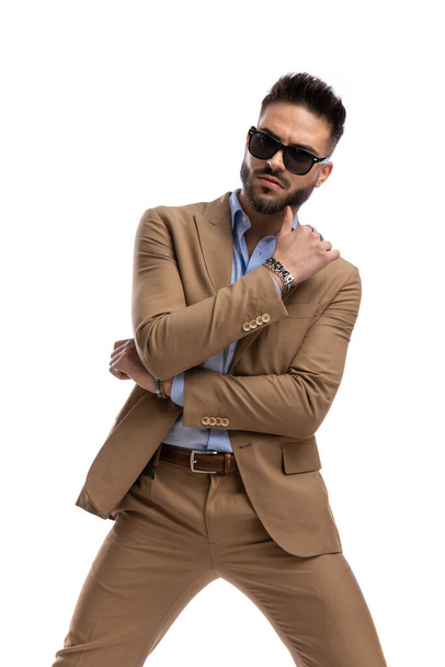 sexy unshaved businessman with glasses holding arms in a fashion pose and looking to side on white background in studio - Photo, Image