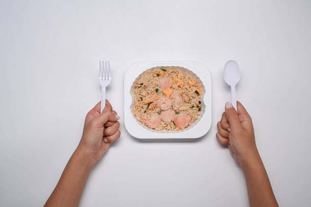 Mujer sosteniendo cuchara y tenedor listo para microondas y comer arroz frito con camarones. - Foto, Imagen