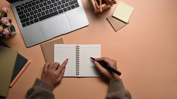 Nad pohled mladá žena drží pero psaní na prázdný notebook. - Fotografie, Obrázek