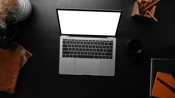 Moderno lugar de trabajo con computadora portátil, taza de café y suministros en la mesa negra. - Foto, imagen