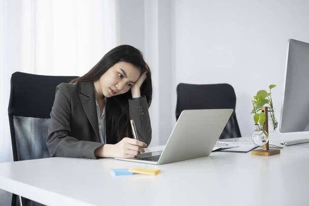 Femme ennuyée employée de bureau travaillant avec un ordinateur portable au bureau. - Photo, image