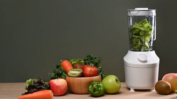 木製のテーブルの上に新鮮な野菜や果物と現代のブレンダー。健康食品のコンセプト. - 写真・画像
