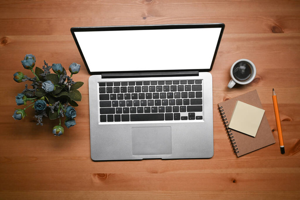 Computador portátil da vista acima, copo de café, caderno e flores na tabela de madeira. - Foto, Imagem