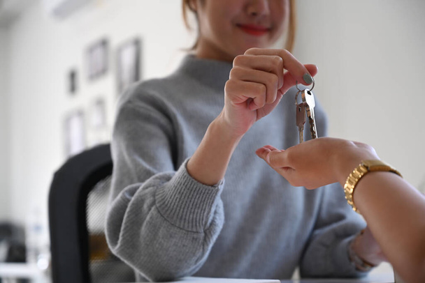Smiling female estate agent giving house keys to customer. Real estate investment concept. - Fotó, kép