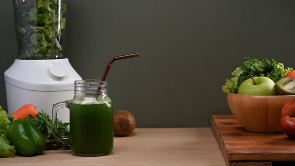 Зеленый овощной смузи, блендер и свежие овощи на деревянном столе. Концепция здорового питания. - Фото, изображение