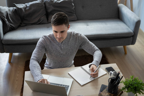 Handsome man freelancer sitting on floor in living room and working with computer laptop.  - Photo, Image