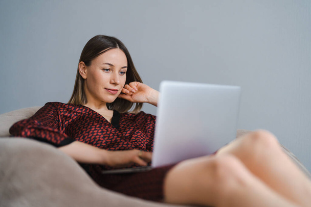 Femme utilisant un ordinateur portable à la maison relaxant - Photo, image