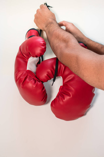 Человек в красных боксерских перчатках держит боксерскую грушу - Фото, изображение