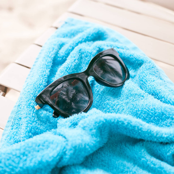 blue towel and sunglasses on the beach - Fotoğraf, Görsel