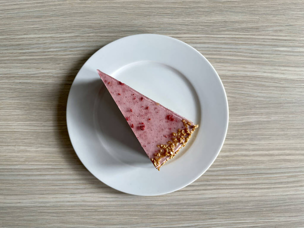 piece of cake on a white plate on a wooden background - Photo, Image