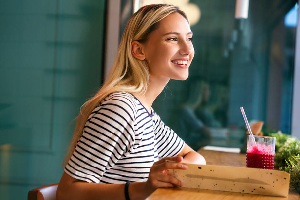 Muotokuva terveestä nuoresta onnellisesta naisesta juomassa mehua kahvilassa. Ihmiset terveys elämäntapa käsite - Valokuva, kuva