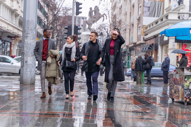Vier multiraciale drukte mensen lopen samen op de regen - Foto, afbeelding