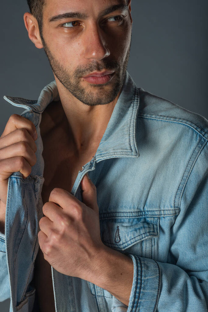 Imagen de un joven macho guapo con abdominales y chaqueta vaquera abierta y jeans. - Foto, imagen