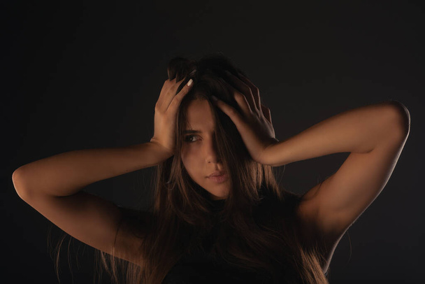Портрет красивої дівчини позує в студії, торкаючись її волосся
 - Фото, зображення