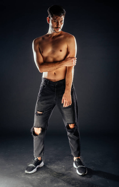 Stylish fashion guy posing topless against dark background - Foto, Bild