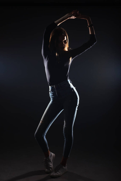 Silhouette picture of a young gorgeous woman posing on black background - 写真・画像