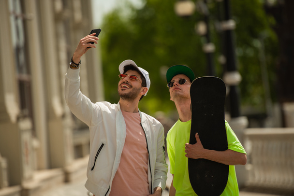 Dos guapos amigos varones sonríen por los selfies - Foto, imagen
