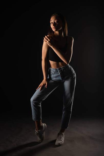 Casual dressed and beabeautiful young girl is posing professionally in studio on black background - Φωτογραφία, εικόνα