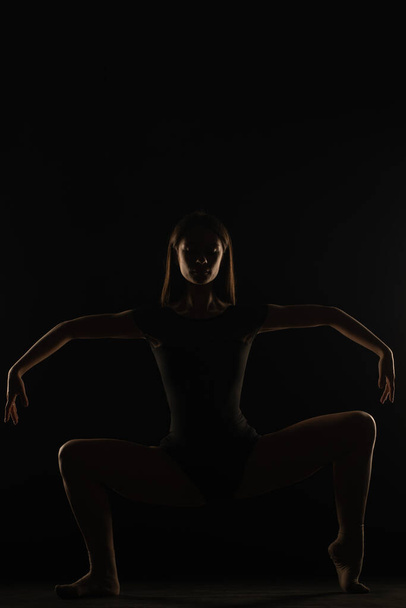 Junge Ballerina hält ihre Haltung großartig, während sie eine asymmetrische Pose auf Silhouette macht - Foto, Bild