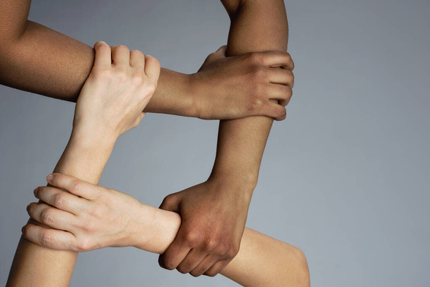 African and Caucasian female hands on gray background. Interracial friendship, care and support. - Foto, imagen