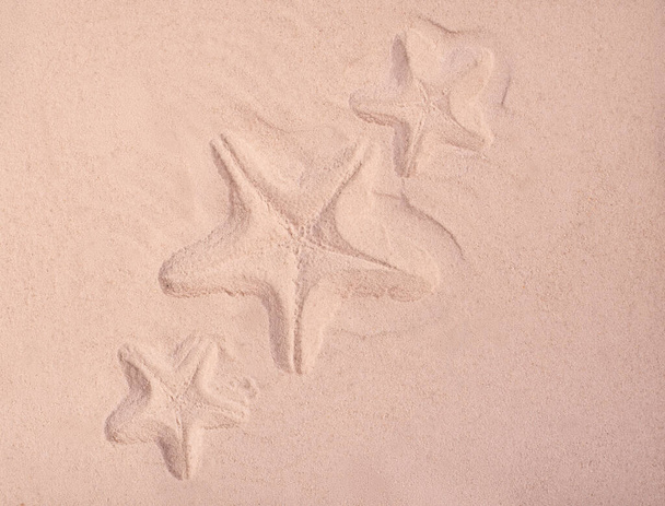 Морские звезды на поверхности песка. Летний фон хорош для морских распродаж или туристических поездок. - Фото, изображение