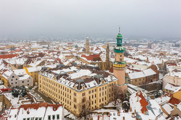 Sopron şehrinin göbeğindeki ikonik Ateş Kulesi ve Keçi Kilisesi 'ni gösteren hava manzarası. Karlı çatıları olan kış şehri.. - Fotoğraf, Görsel