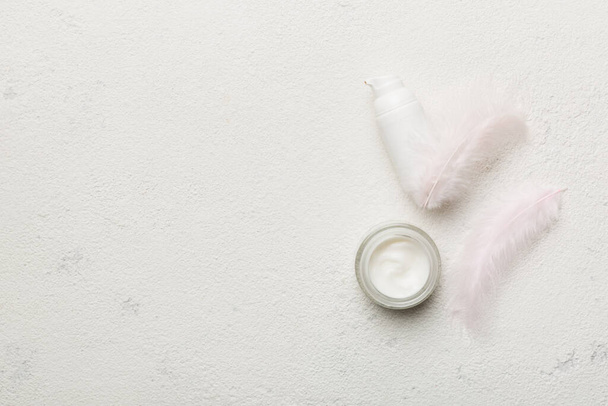 Set of skin care serums on pink pastel background with ostrich feathers. Spa cosmetic product, cream jar, branding mock up, top view with copy space. - Photo, Image
