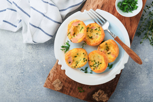 Egg muffins with green onions, bacon, cheese and tomatoes on white plate on light background. Healthy high protein and low carb breakfast, ready to eat. - Фото, зображення