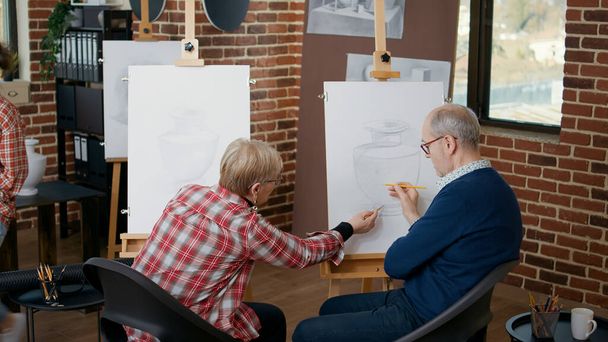 Мужчина и женщина в общественном центре рисуют вазу модели - Фото, изображение