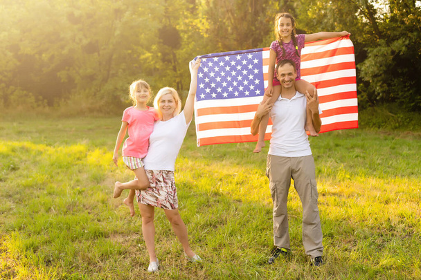 Happy family in field with USA, american flag on back. - Photo, Image