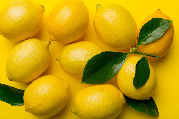Many fresh ripe lemons as colored background, top view. Elegant background of lemon and lemon slices Top view flat lay. - 写真・画像