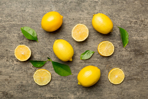 Veel verse rijpe citroenen als gekleurde achtergrond, bovenaanzicht. Elegante achtergrond van citroen en citroen plakken Bovenaanzicht plat lay. - Foto, afbeelding