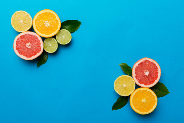 Φόντο φρούτων. Πολύχρωμα φρέσκα φρούτα στο χρωματιστό τραπέζι. Πορτοκαλί, λεμόνι, γκρέιπφρουτ Χώρος για κείμενο υγιή έννοια. Επίπεδο lay, πάνω όψη, αντιγραφή χώρου. - Φωτογραφία, εικόνα