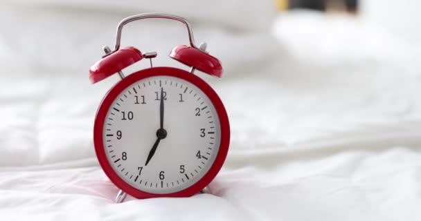 Red alarm clock for seven in morning is on bed in bedroom - Footage, Video