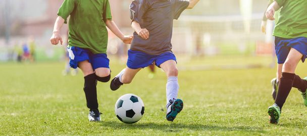 Çocuklar Futbol Turnuvası. Çocuklar Futbol Maçı Düellosunda yarışıyor. Topa vurma anı. Genç Tekmeleyen Top. Okul çocukları Çimen Sahasında Klasik Futbol Topu koşuyor - Fotoğraf, Görsel