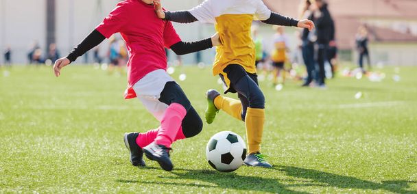 School girl and boy playing soccer game. Kids having fun and playing football match. Girl in pink soccer uniform kicking ball - Photo, Image