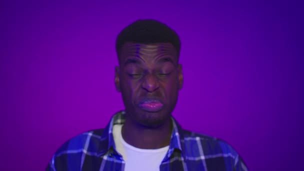 Disgustato africano uomo accigliato sentimento cattivo odore su sfondo viola - Filmati, video