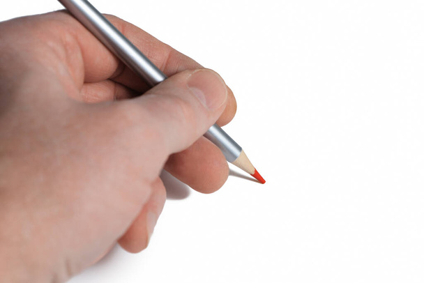 Lápis vermelho na mão esquerda masculina sobre papel branco fundo branco. Conceito do dia da mão esquerda. Espaço de cópia - Foto, Imagem