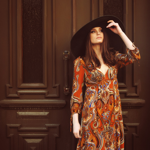 portrait of a beautiful girl in a dress with a hat at the door - Фото, изображение