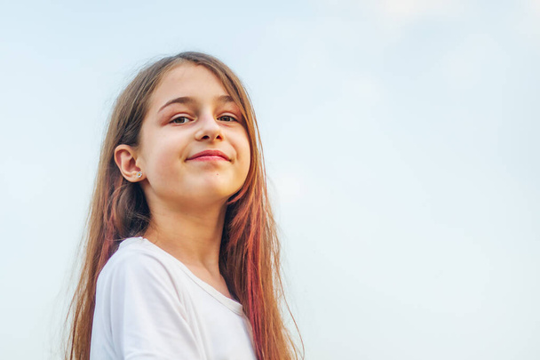 Girl 11 years old. Portrait of a teenage girl with long hair against the sky. - Photo, Image