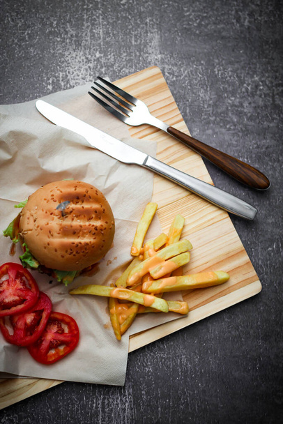 Pork burgers served on paper With french fries and tomatoes, it's an American dish. - Photo, Image