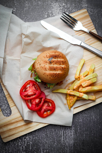 Burgers, frites, tomates rouges servies sur une table grise. - Photo, image